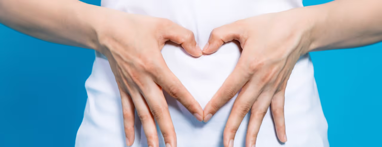 Über einem Bauch wird ein Herz mit den Händen geformt