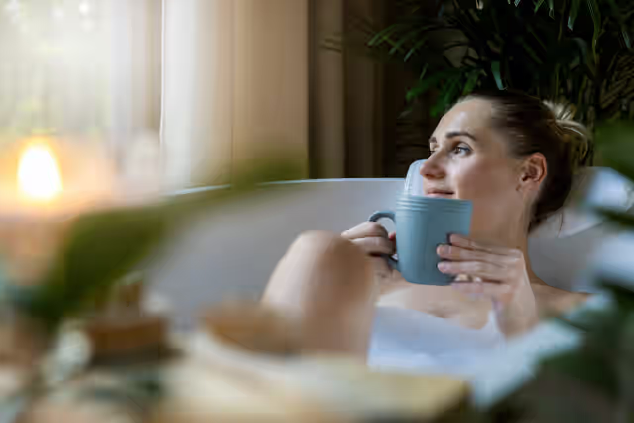 Frau in einer Badewanne mit Tasse in der Hand