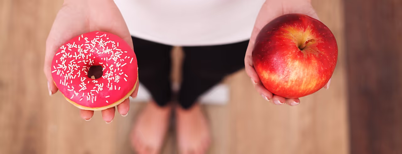 Frau hält Doughnut und Apfel