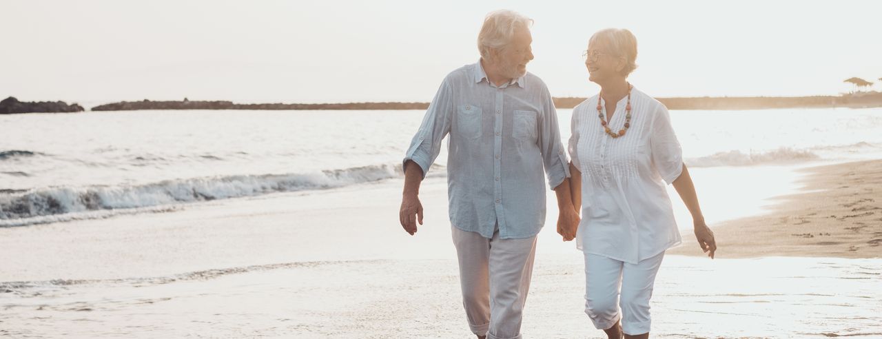 Senioren Paar läuft händchenhaltend über den Strand