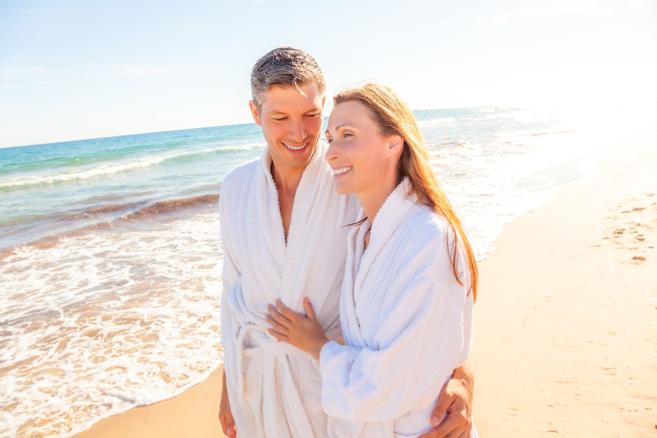 Ein Paar im Bademantel spaziert am Strand