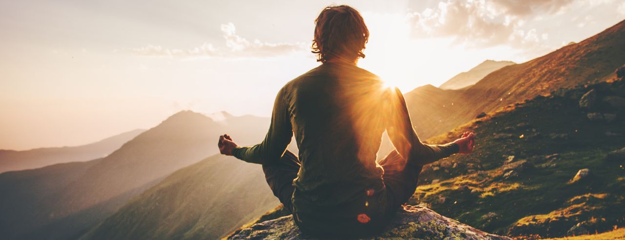 Un hombre medita en una montaña al amanecer