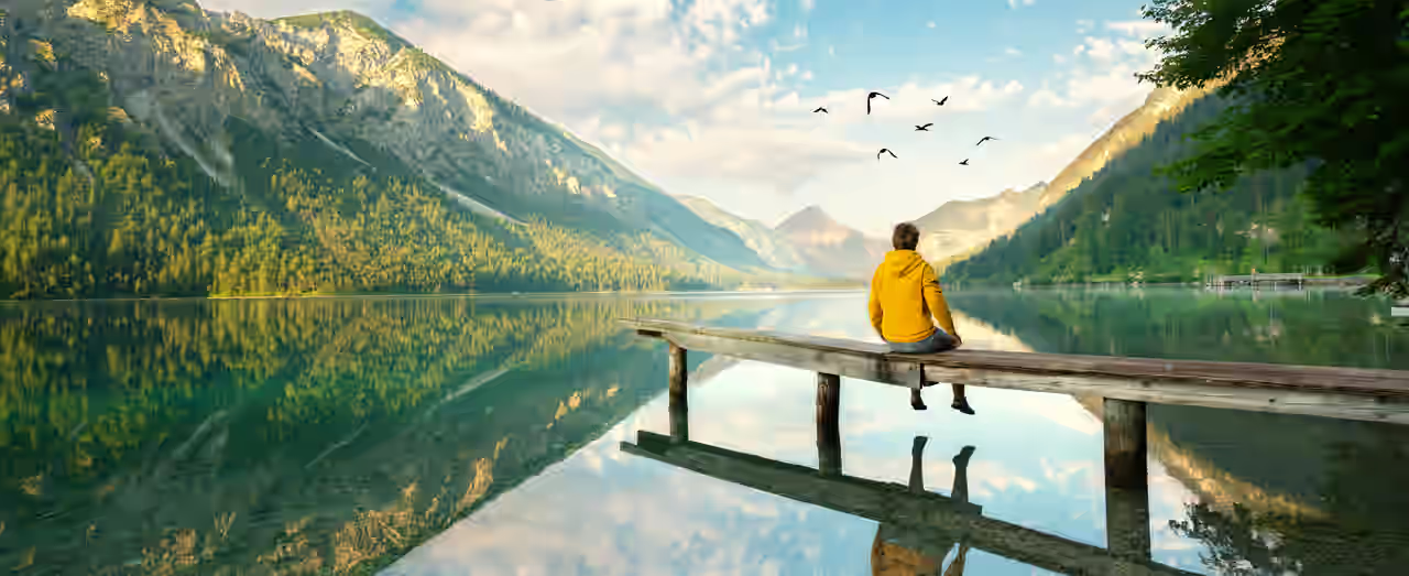 Eine Person sitzt auf einem Steg über einem Bergsee