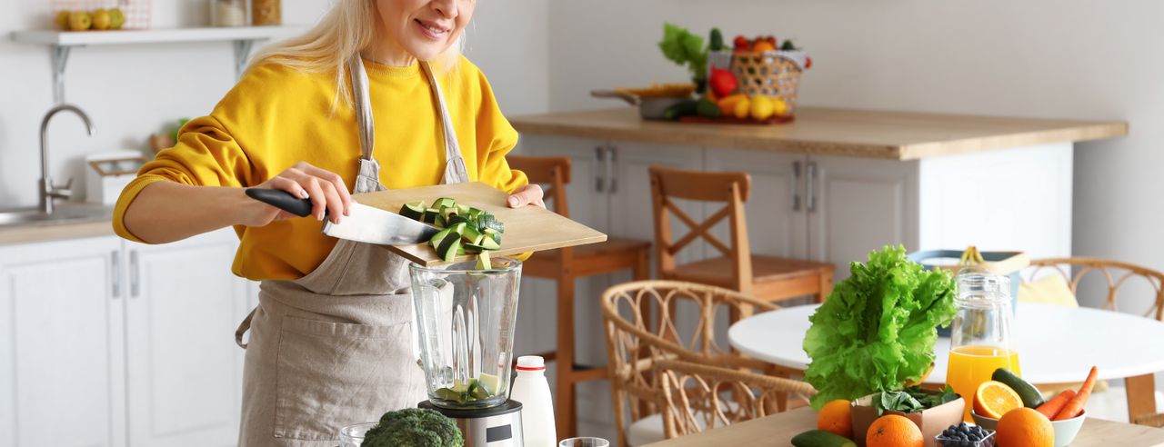 Frau verarbeitet Lebensmittel für eine Basenfasten Kur im Mixer