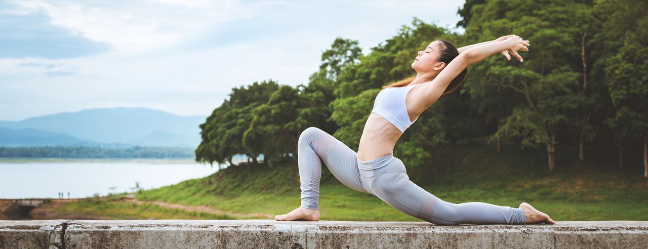 En kvinna i en yogaposition utövar yoga utomhus mot kronisk ryggsmärta