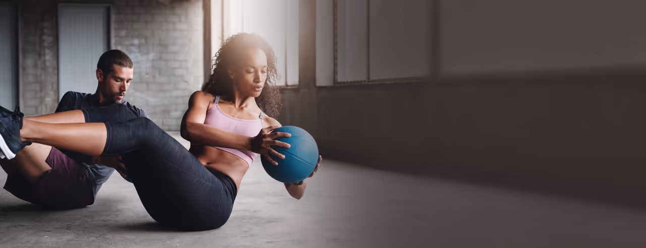 A man and a woman training with an exercise ball