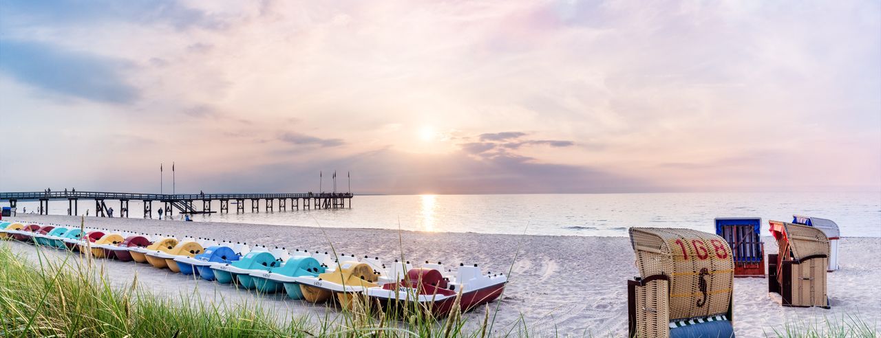 Der Weissenhäuser Strand bei Sonnenuntergang mit Tretbooten am Strand und den typischen Strandkörben