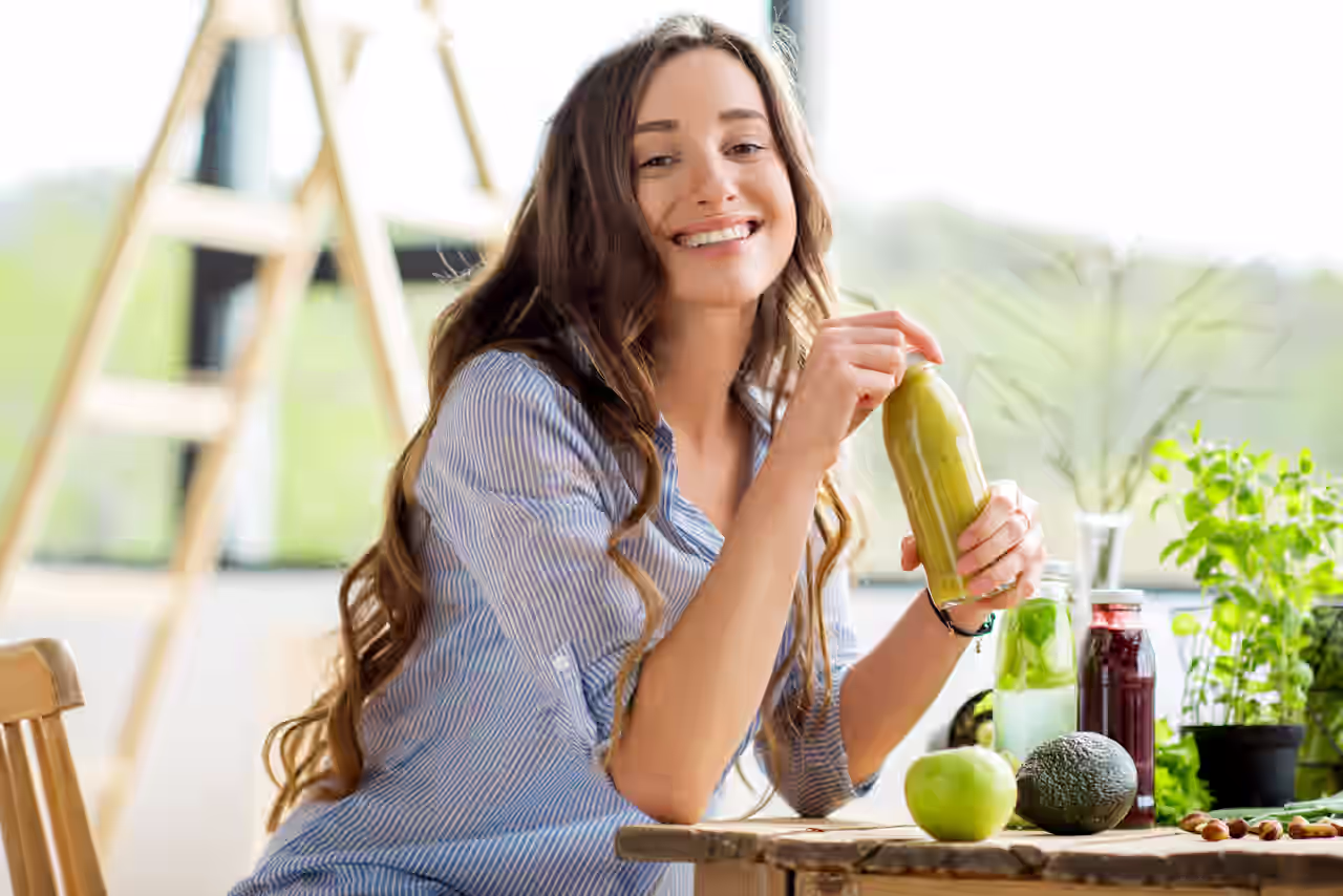 Frau, die an einem Tisch sitzt und einen Smoothie in der Hand hält