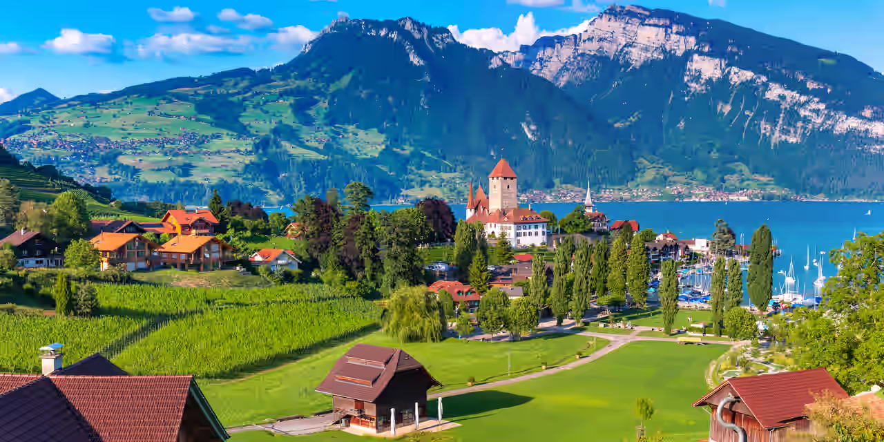 Häuser, Kirche und Seglerhafen am See mit Blick auf die Berge