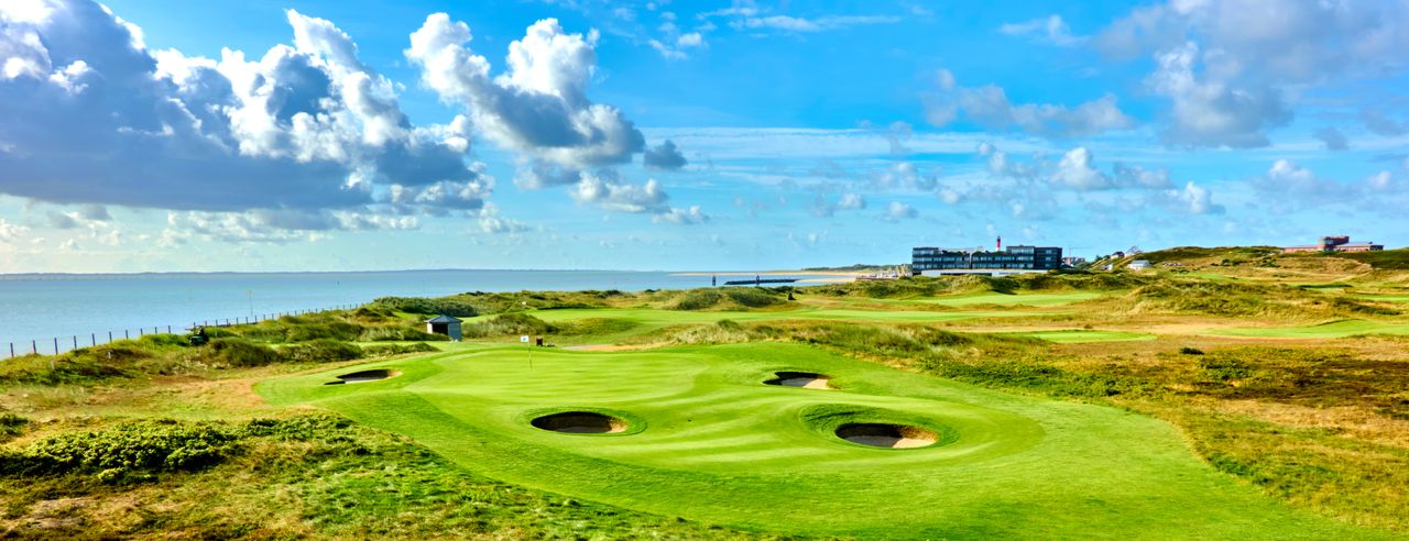 Golfplatz mit dem Meer und einem Hotel im Hintergrund