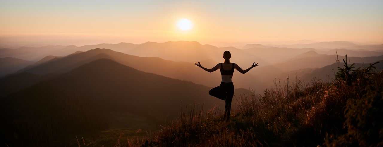 Frau steht in einer Yogapose in den Bergen während ihres Yoga Wochenendes