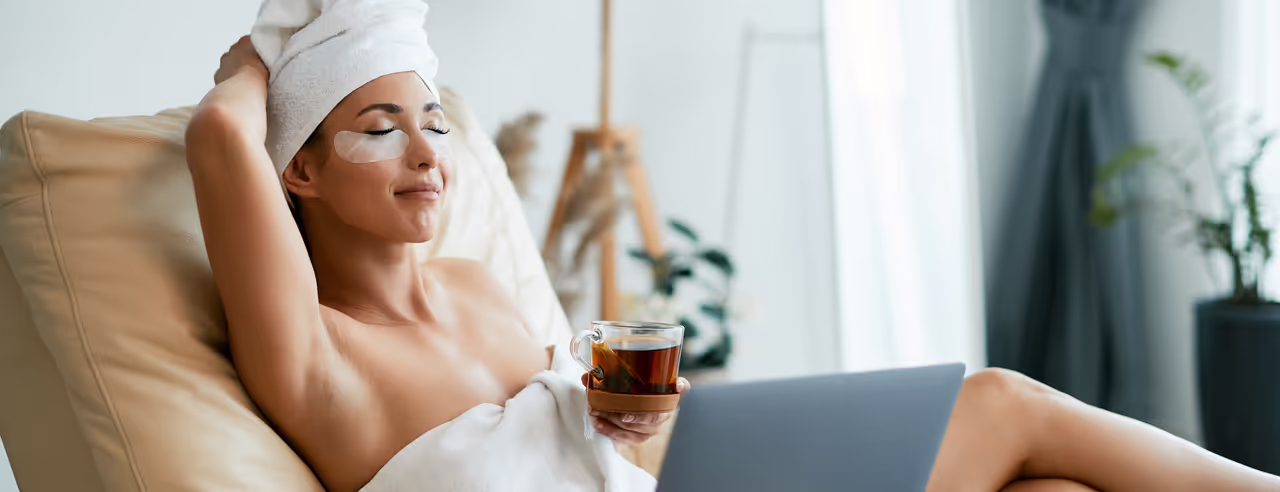 Eine Frau liegt entspannt auf einem Sofa und trinkt Tee