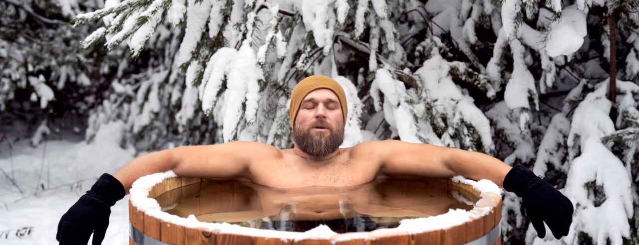 Ein Mann in einer Eistonne vor einer verschneiten Tanne.