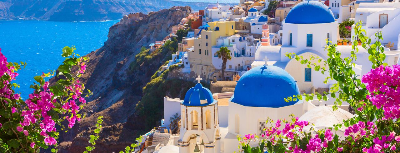 White houses with blue roofs and the sea in the background show the typical Greece