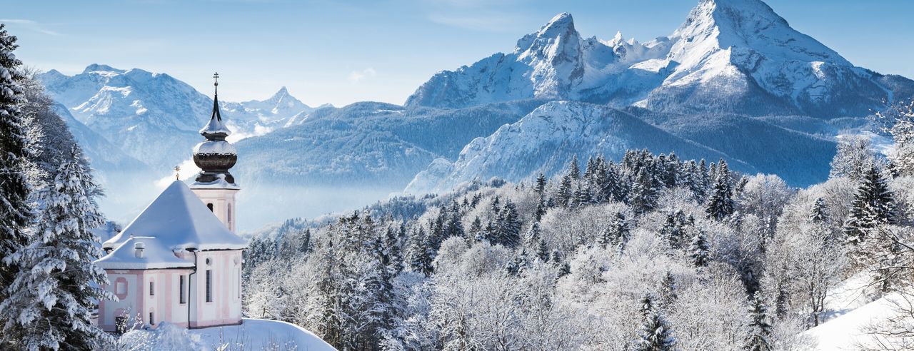 Berge, Bäume und Kirche mit Schnee bedeckt