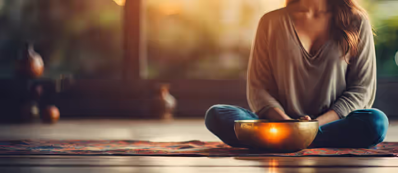 Yoga e Ayurveda; una donna siede nella posizione del loto davanti a una ciotola per cantare