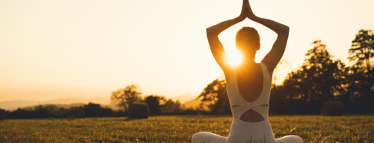 Eine Frau praktiziert in der schönen Natur von Rheinland-Pfalz Yoga in Ihrem Urlaub