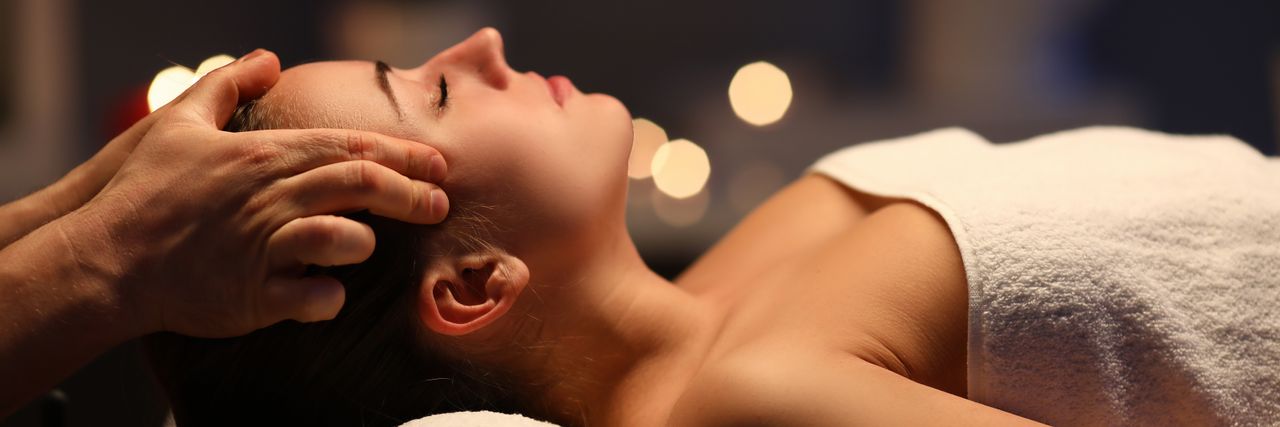 Eine Frau liegt entspannt auf der Massageliege und erhält eine Kopfmassage