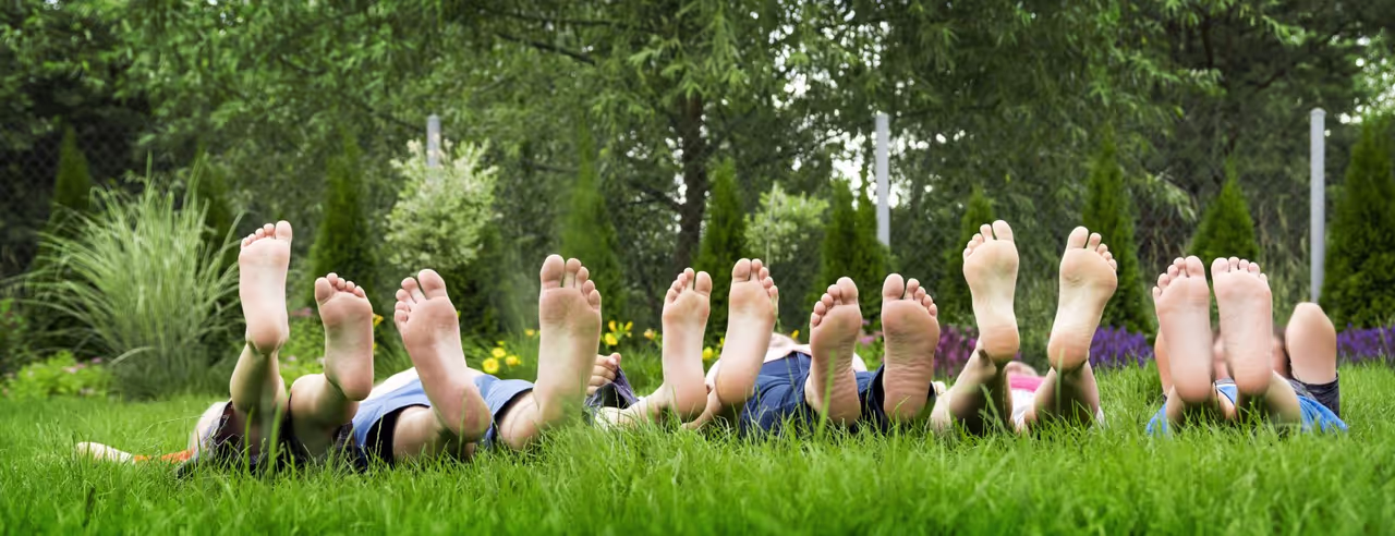 Personen liegen auf der Wiese und man sieht die Fußunterseite