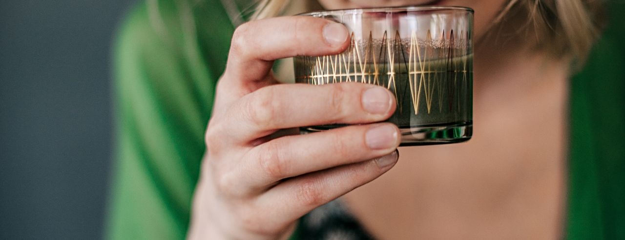 Frau hält ein Glas mit Getränk für eine Fastenkur