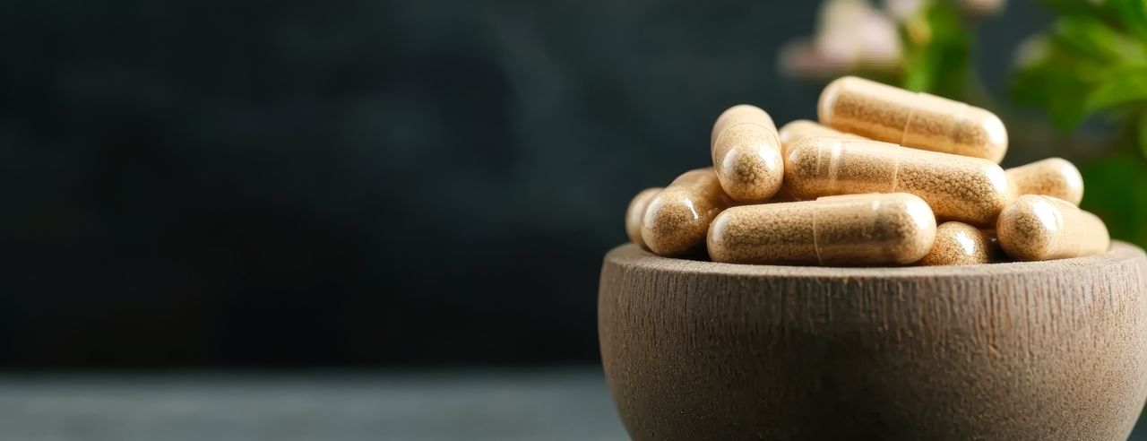 En un cuenco de madera hay varias cápsulas transparentes con un polvo amarillento en su interior.