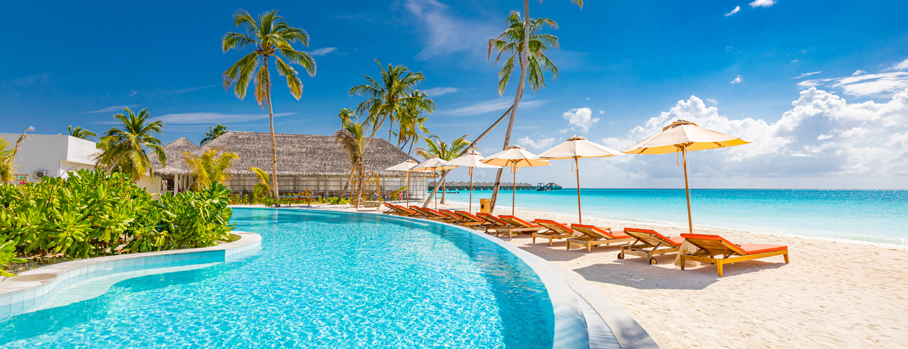 Pool am Meer mit Palmen, Sonnenschirmen und Liegen