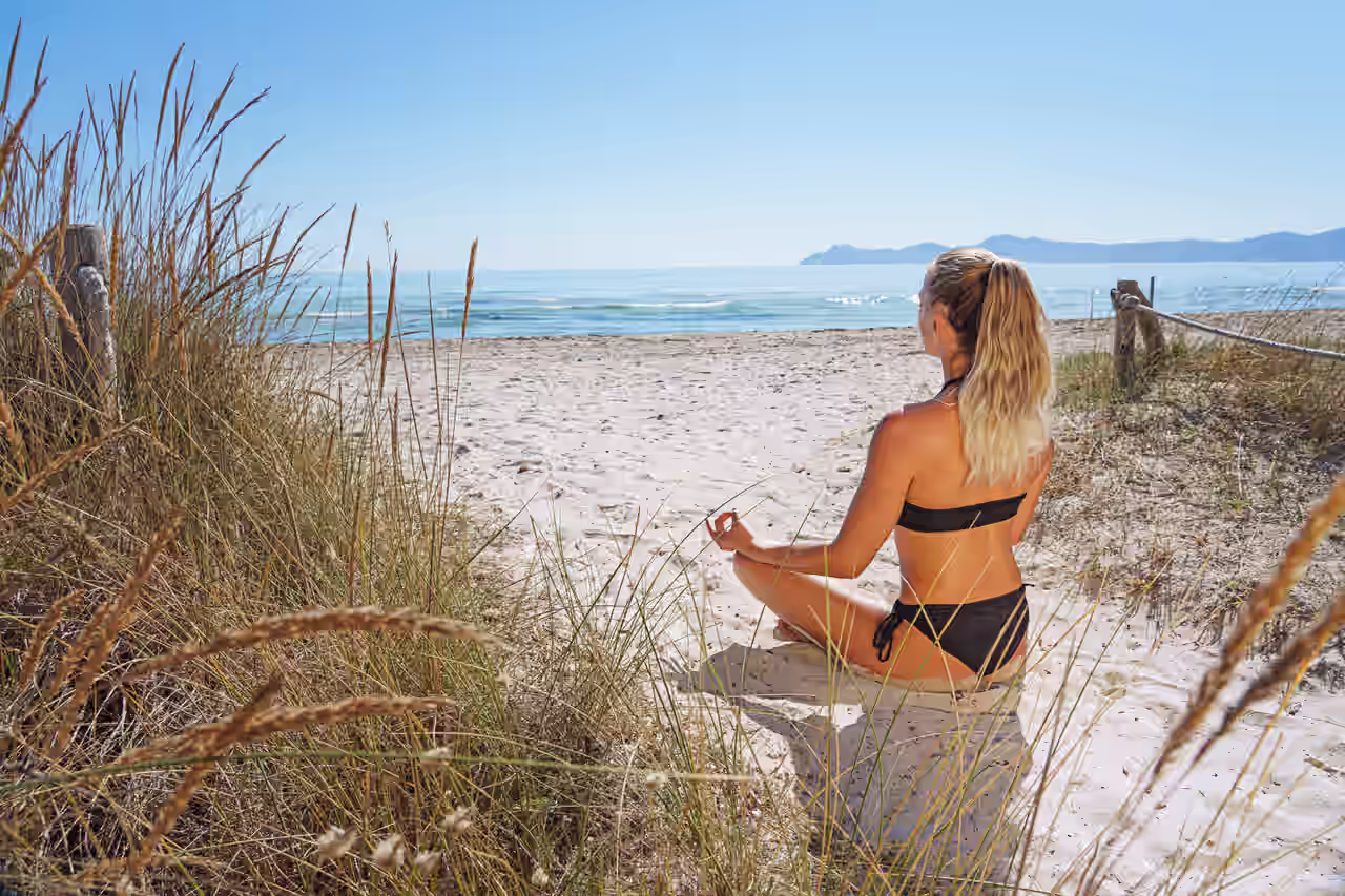 Eine Frau streckt mit Blick auf die Ostsee die Arme weit aus
