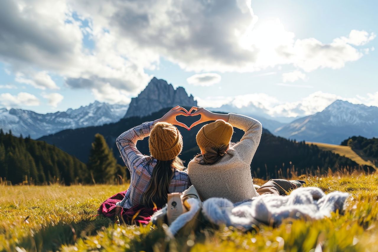 Ein Paar liegt bei einem schönen Herbstnachmittag auf einer Wiese und bestaunt die Bergwelt