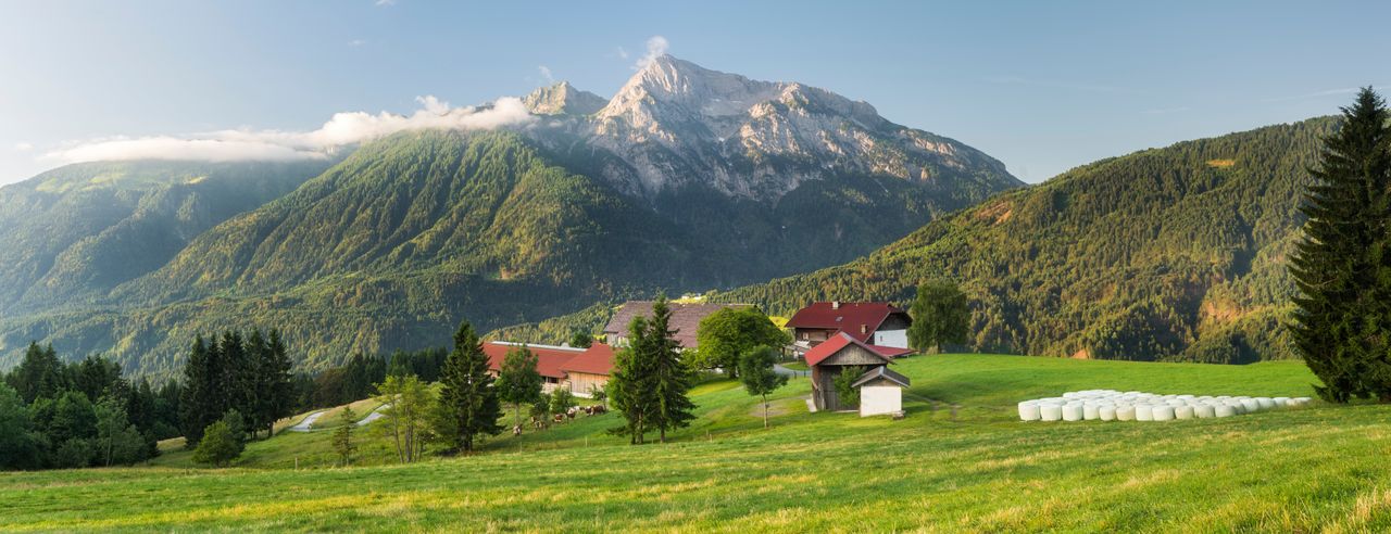 Ein paar Häuser auf einem Feld mit majestätischen Bergen im Hintergrund