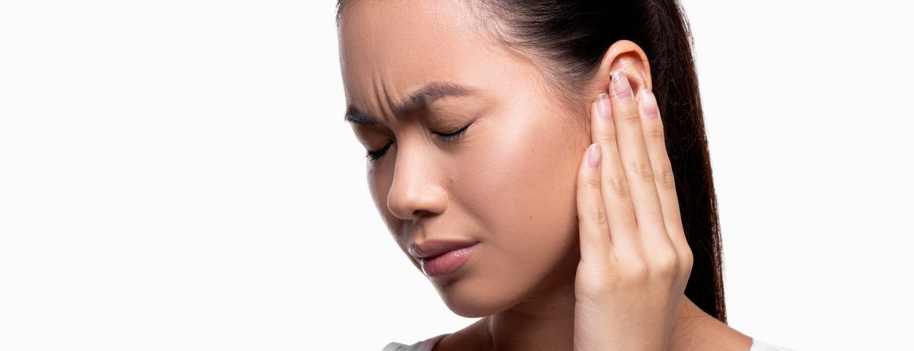 Frau mit Tinnitus hält sich schmerzerfüllt ihr Ohr