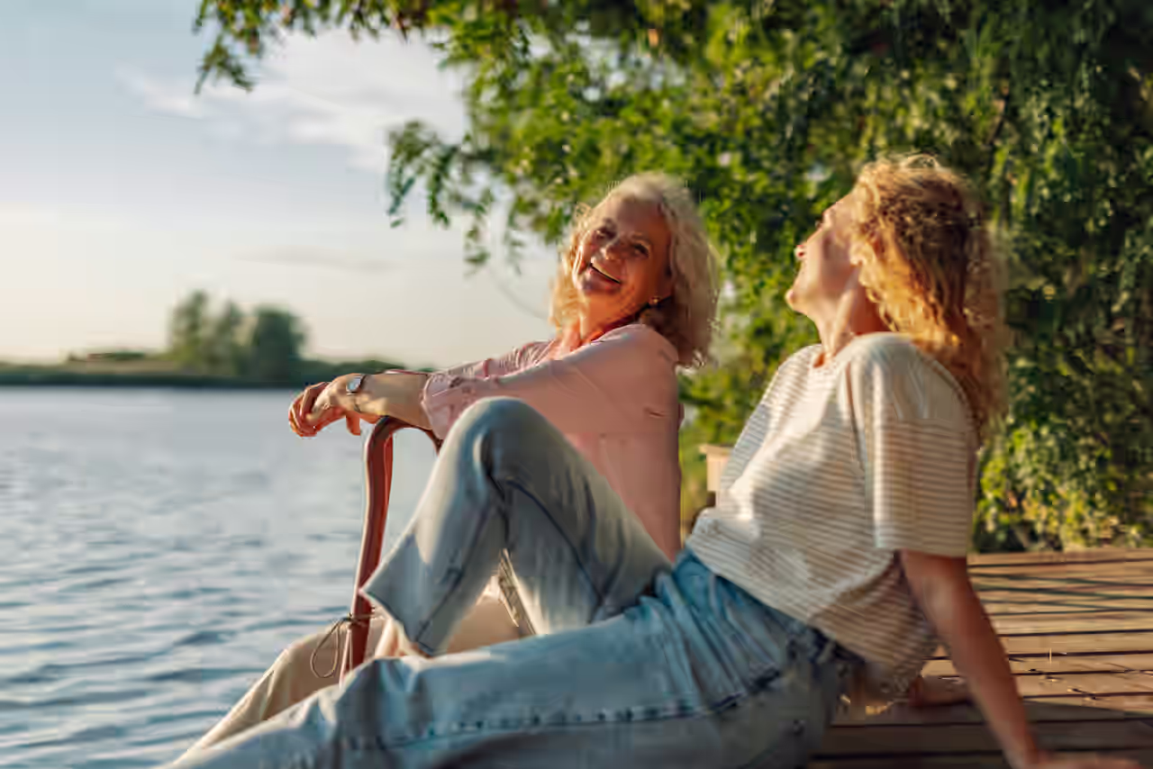 Mutter und Tochter sitzen auf einem Steg am See