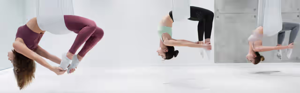 Drei Frauen in Yogatüchern üben Aerial Yoga