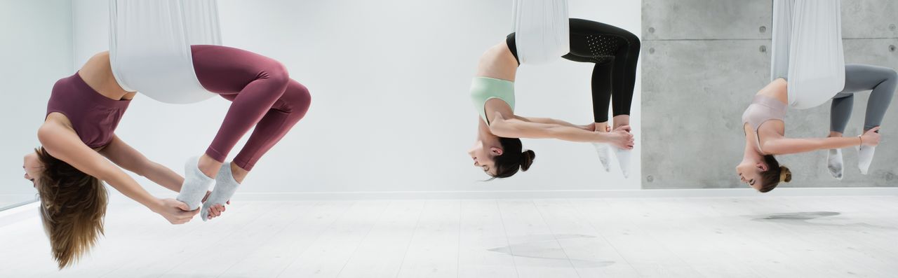 Drei Frauen in Yogatüchern üben Aerial Yoga
