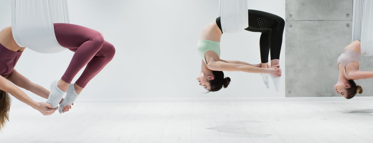 Drei Frauen in Yogatüchern üben Aerial Yoga