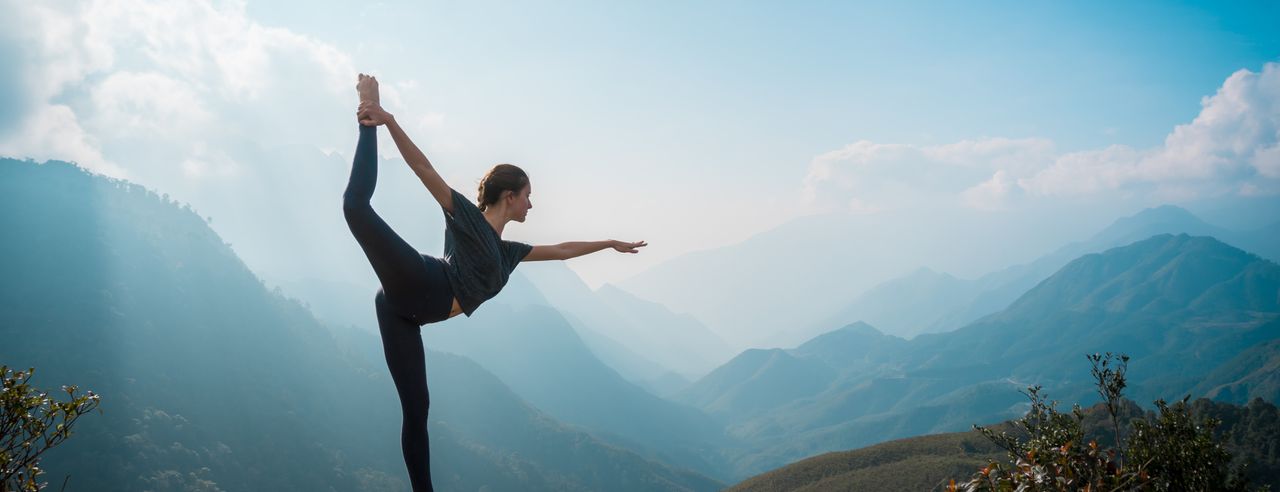 Eine Frau praktiziert auf einem Berg Outdoor Yoga