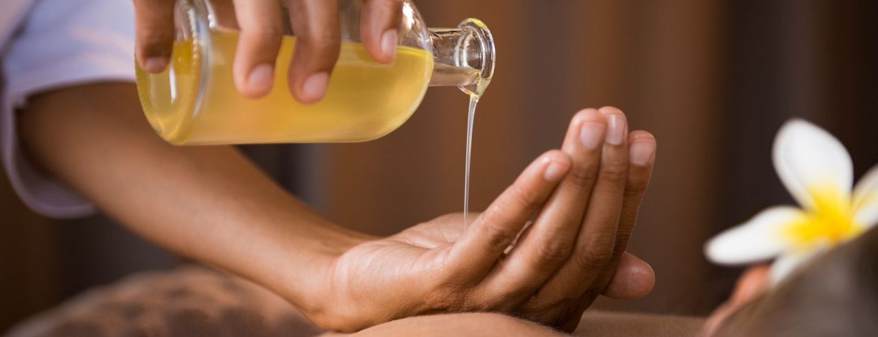 Ayurveda Therapeutin gießt Öl aus einer Flasche in ihre Hand