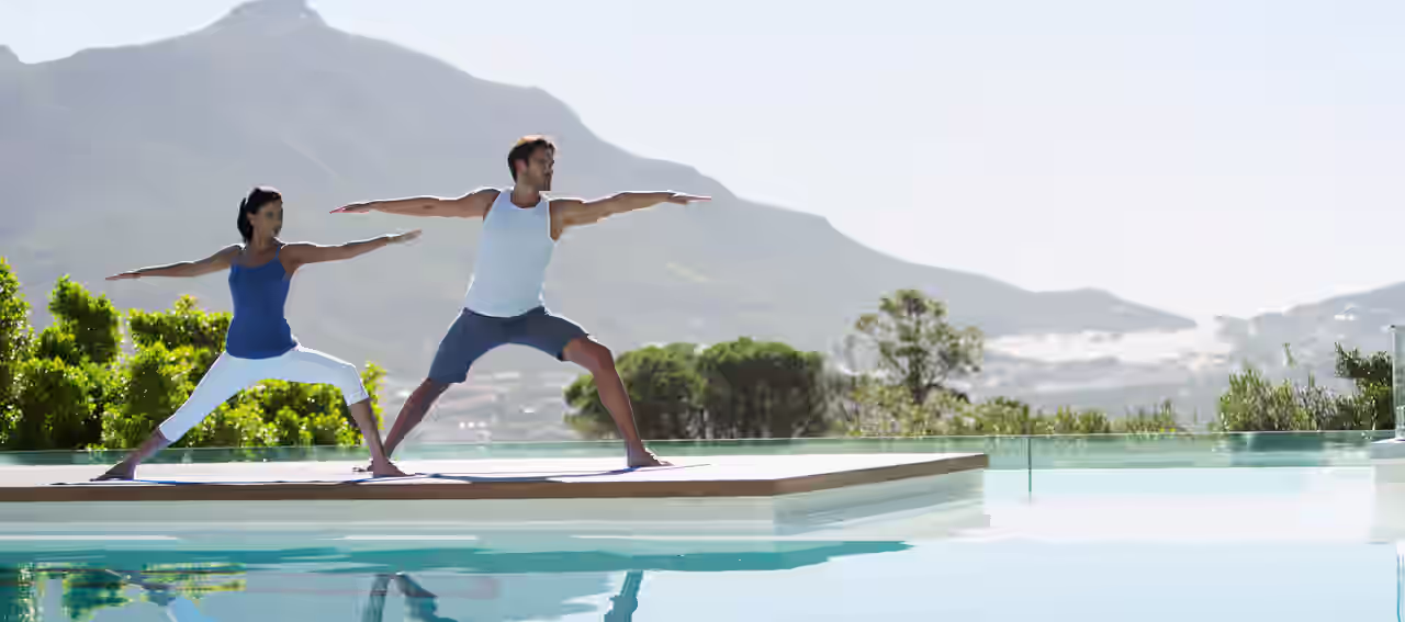 Frau macht Yoga am Pool ihres Yoga und Wellness Hotels