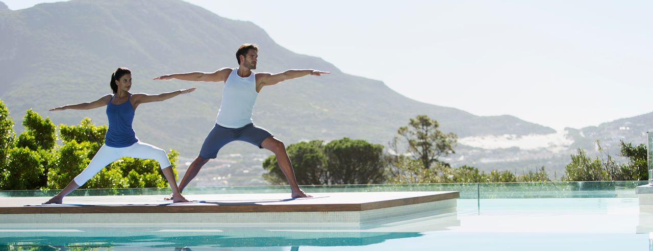 Frau macht Yoga am Pool ihres Yoga und Wellness Hotels