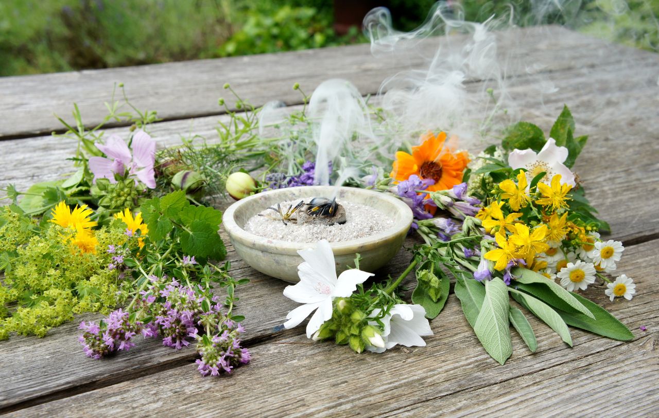Naturheilkunde - Blumen und Kräuter rund um eine Schale mit räucherndem Weihrauch