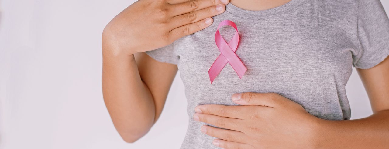Een vrouw houdt het roze lint tegen haar borst