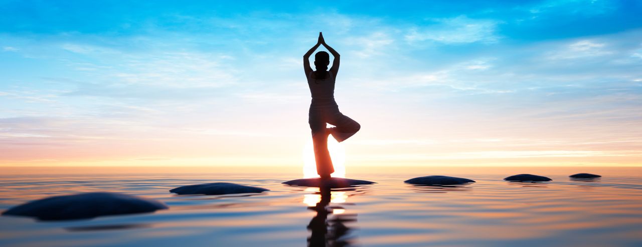 Person im Sonnengruß am Meer, in einem Wellnesshotel mit Yoga