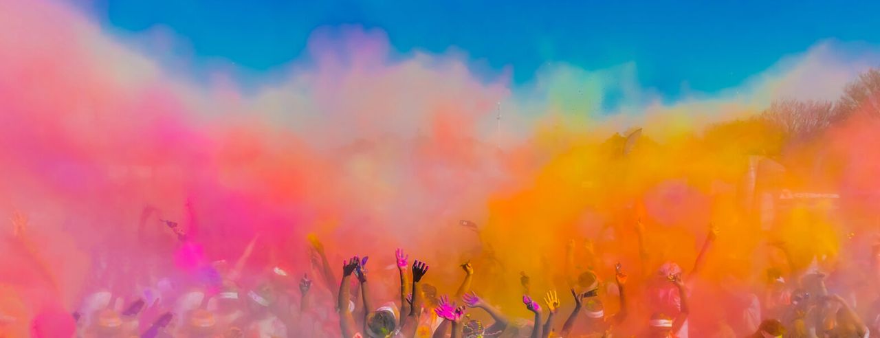Viele Menschen schmeißen Farbpulver in die Luft beim Holi Fest