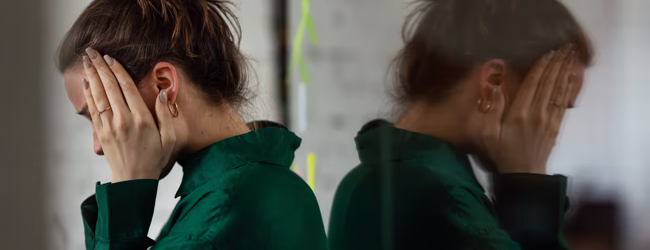 An exhausted woman holds her hands to her face