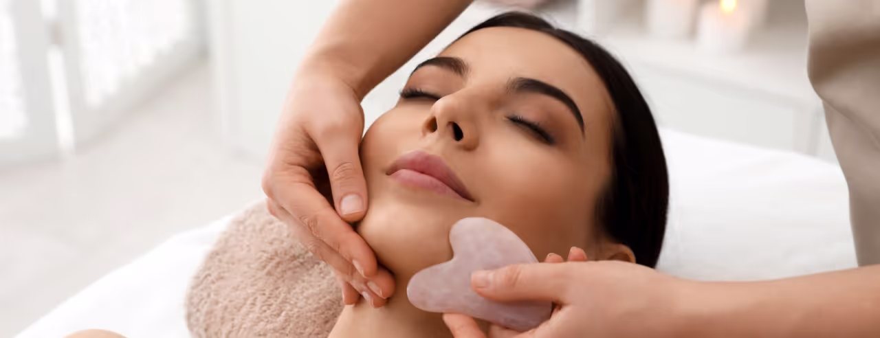 Eine Frau bei einer Gua Sha Gesichtsbehandlung