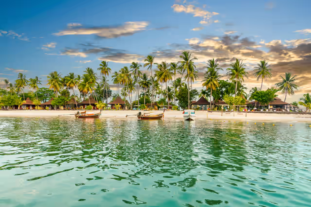 Strand mit Bungalows am Meer zwischen Palmen