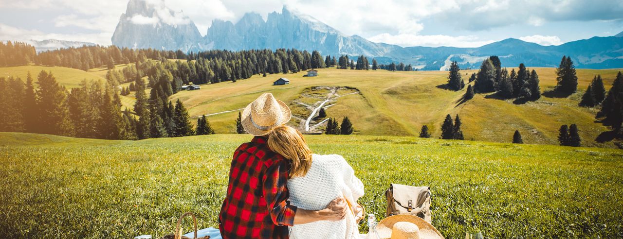 Paar picknickt auf Bergwiese mit Blick auf die Berge