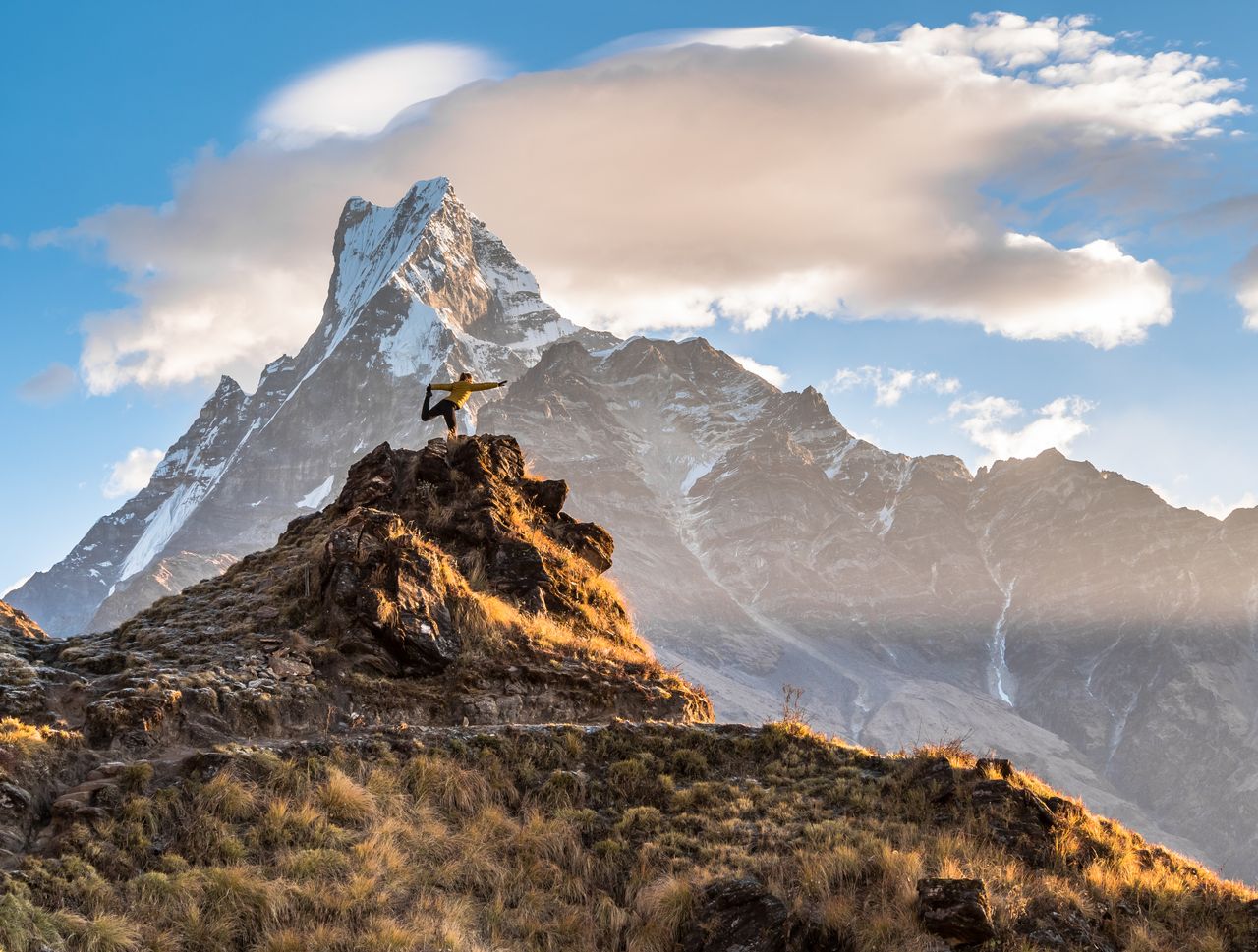Eine Frau praktiziert Yoga auf einer Gipfelspitze des Himalayas