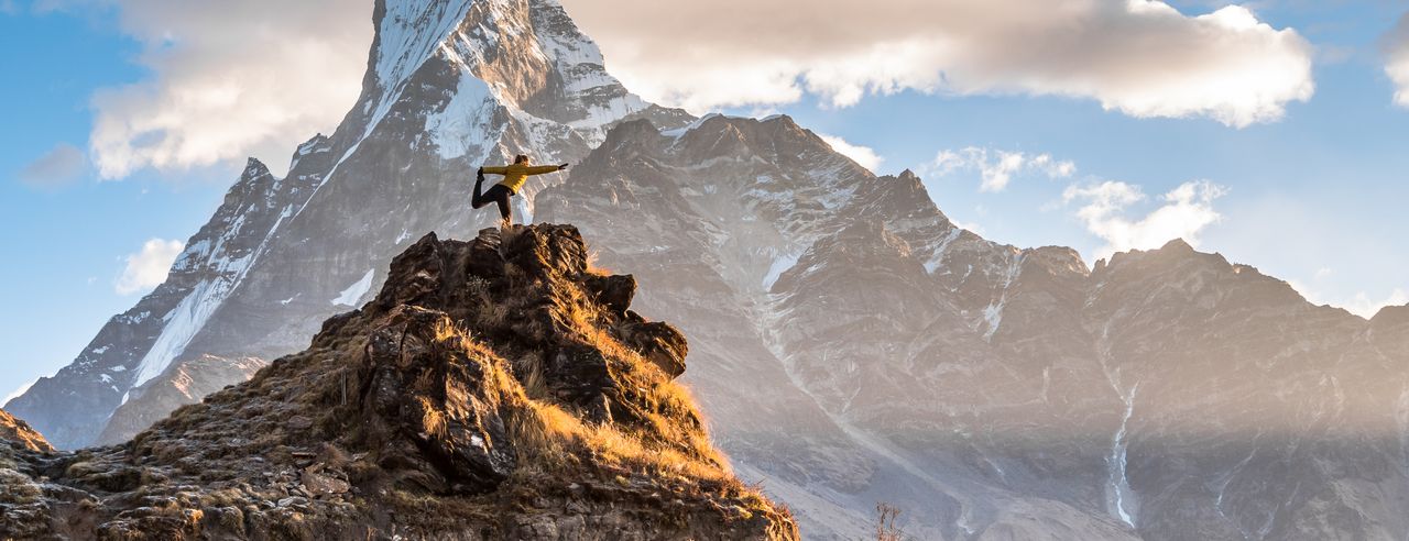 Eine Frau praktiziert Yoga auf einer Gipfelspitze des Himalayas