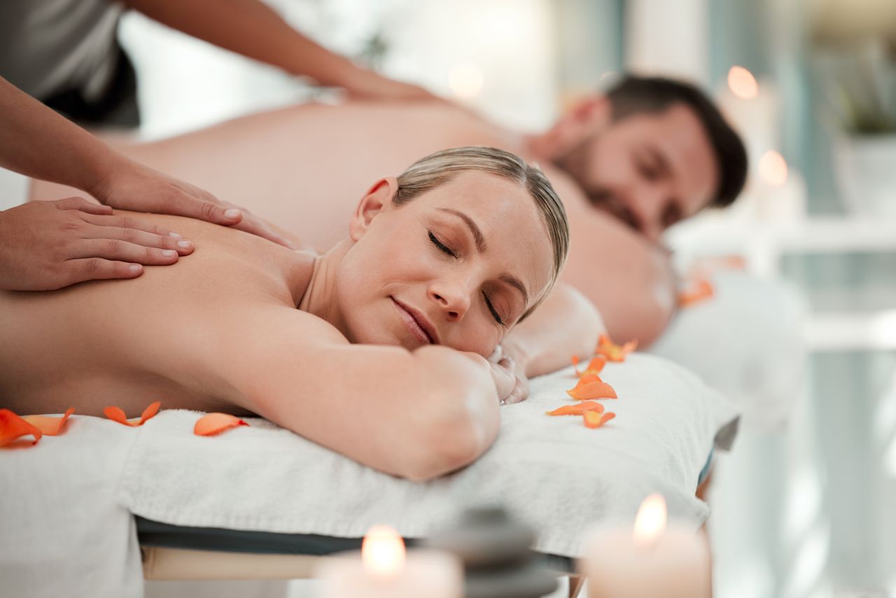 Frau und Mann liegend aus Massagebänken. Die Frau wird massiert.