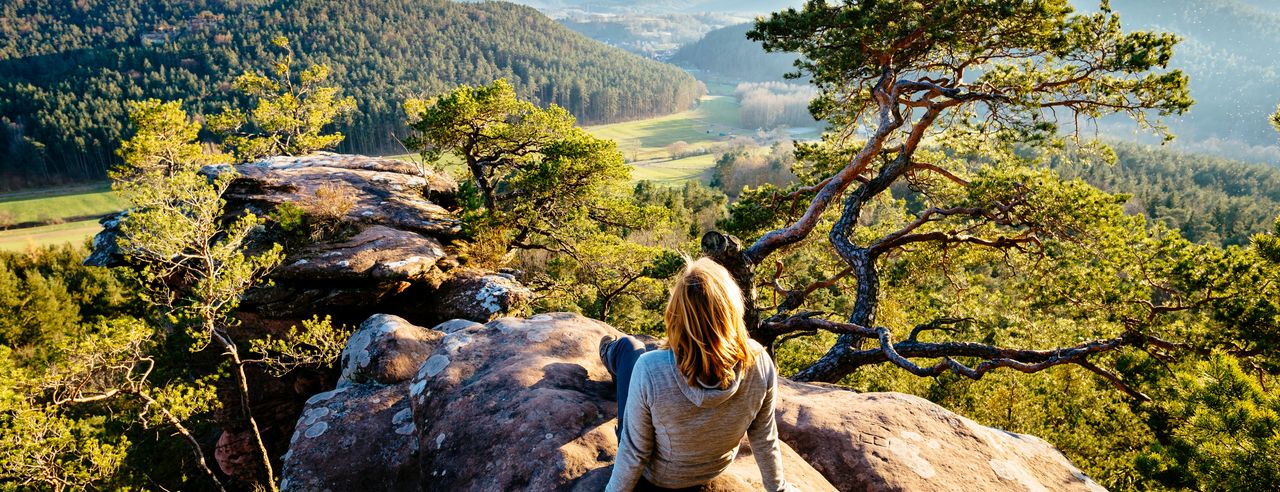 Frau auf Felsen mit Blick auf Landschaft in Rheinland-Pfalz